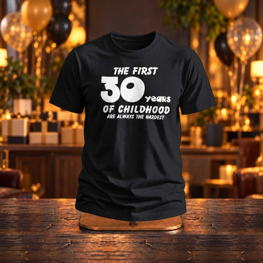 The First 30 Years of Childhood T-shirt in black on a wooden stand at a birthday party with gold and black balloons - funny 30th birthday gift