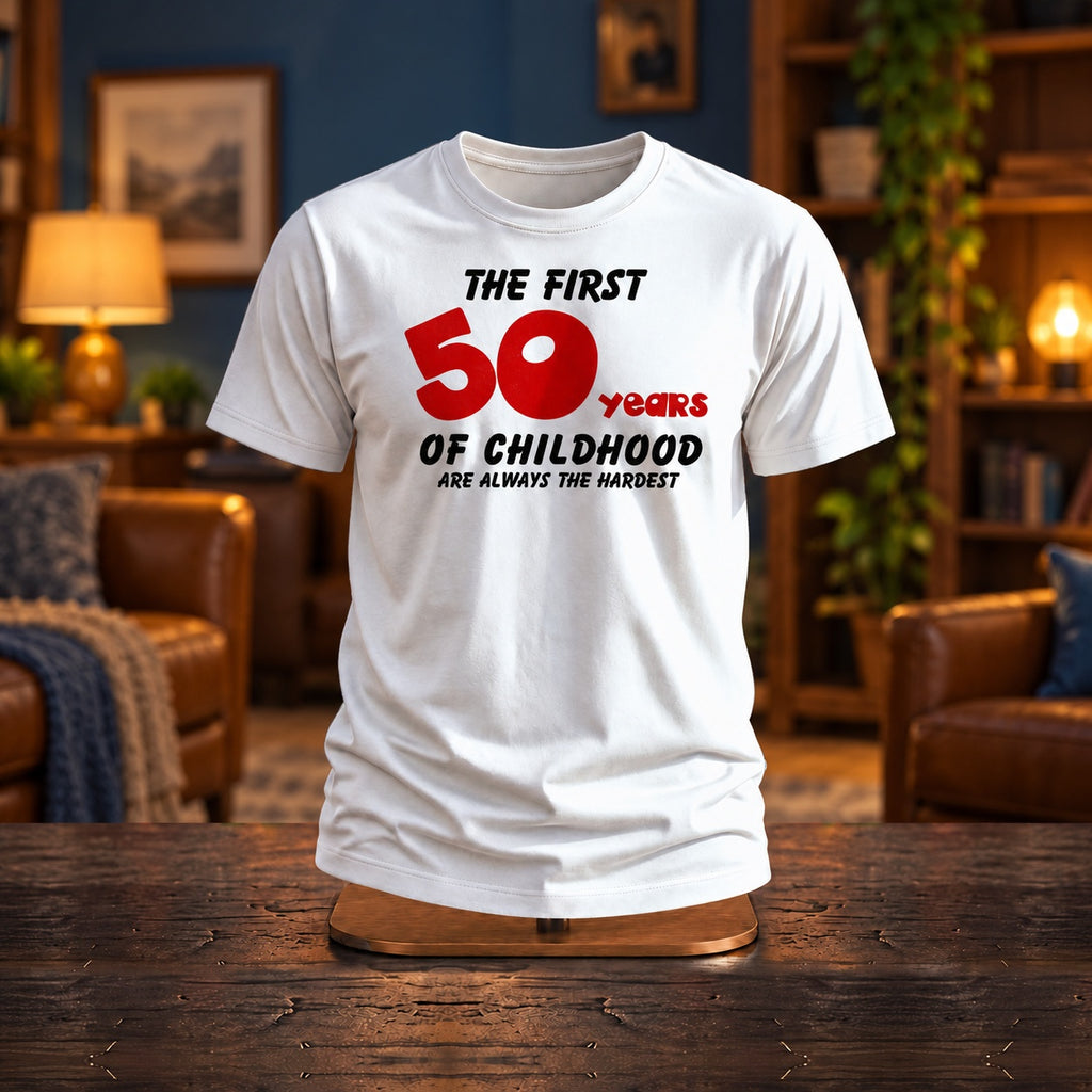 The First 50 Years of Childhood T-shirt in white with a red 50 on a wooden stand in a cosy living room with warm lamps - funny 50th birthday gift