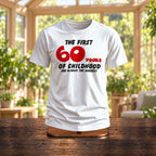 The First 60 Years of Childhood T-shirt in white with a red 60 on a wooden stand in a sunny garden room - funny 60th birthday gift