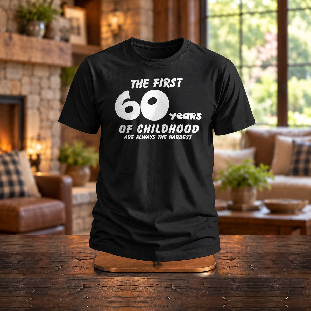 The First 60 Years of Childhood T-shirt in black on a wooden stand by a stone fireplace - funny 60th birthday gift