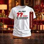 The First Years of Childhood personalised T-shirt in white with red numbers and a PERSONALISATION tag on a wooden stand in a festive living room - enter any age, birthday gift
