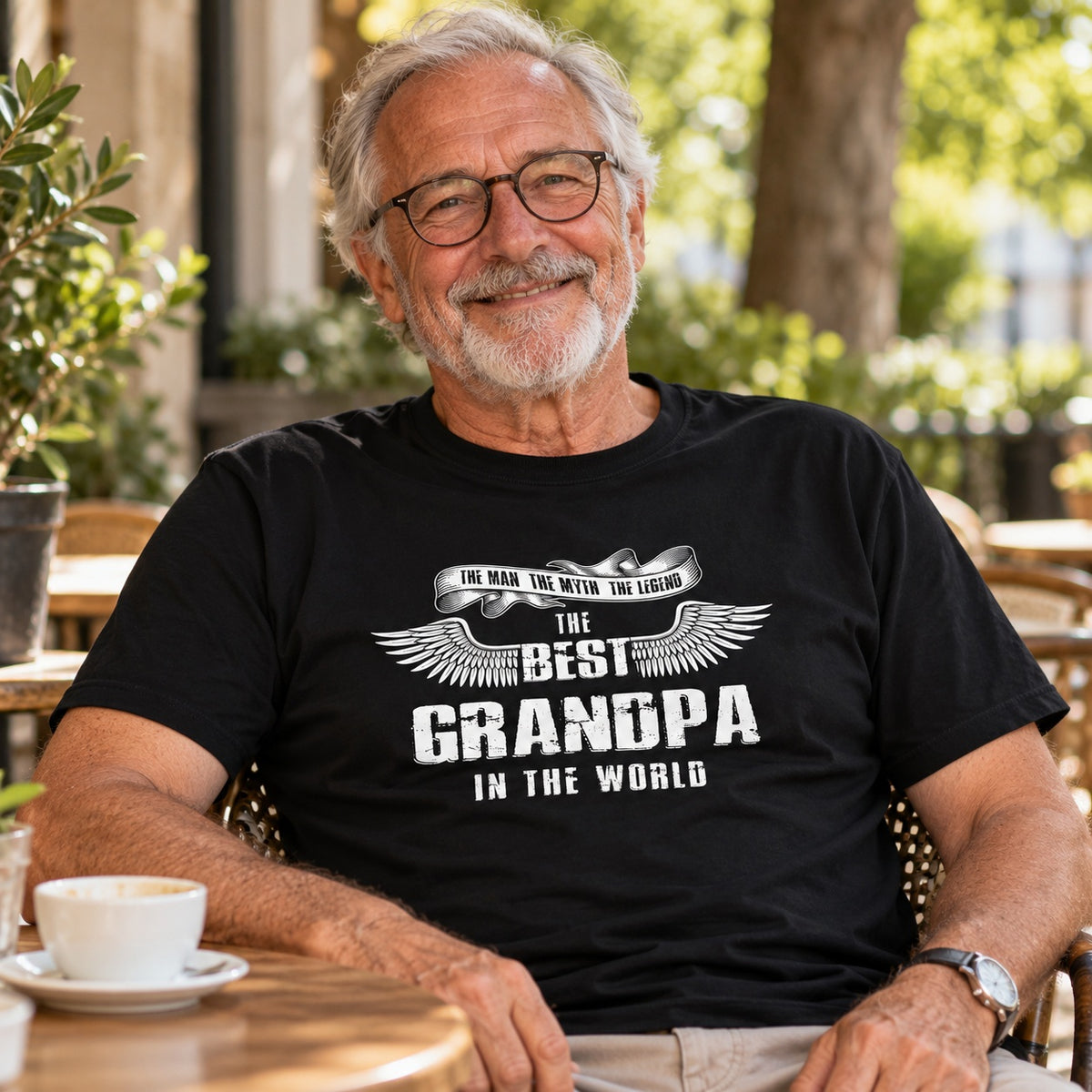 The Best Grandpa In The World wings T-shirt in black - smiling grandpa at a café table with a cup of coffee, gift for grandpa from the grandkids