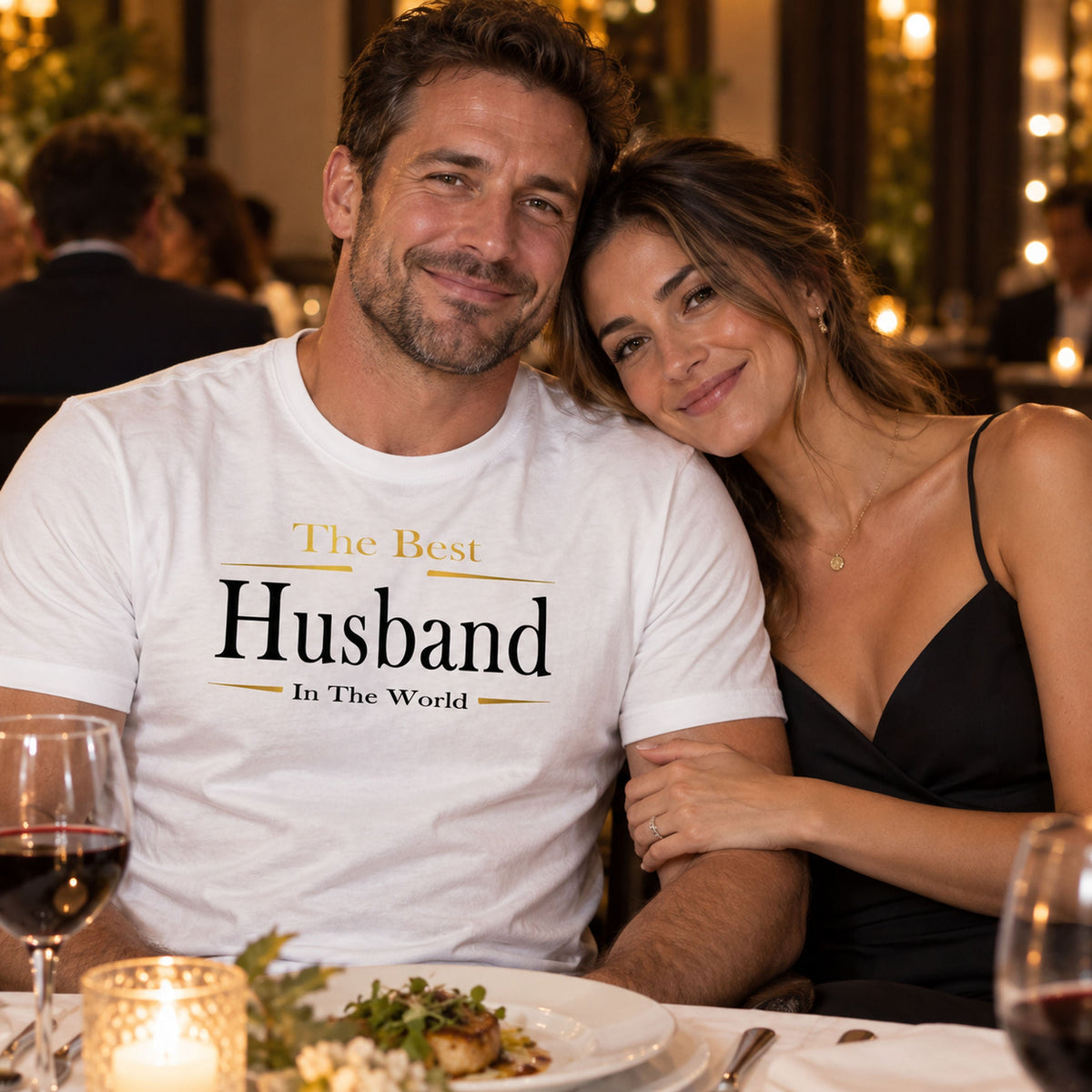 Husband in a white The Best Husband In The World Exclusive t-shirt with gold lettering at a restaurant date night with his wife