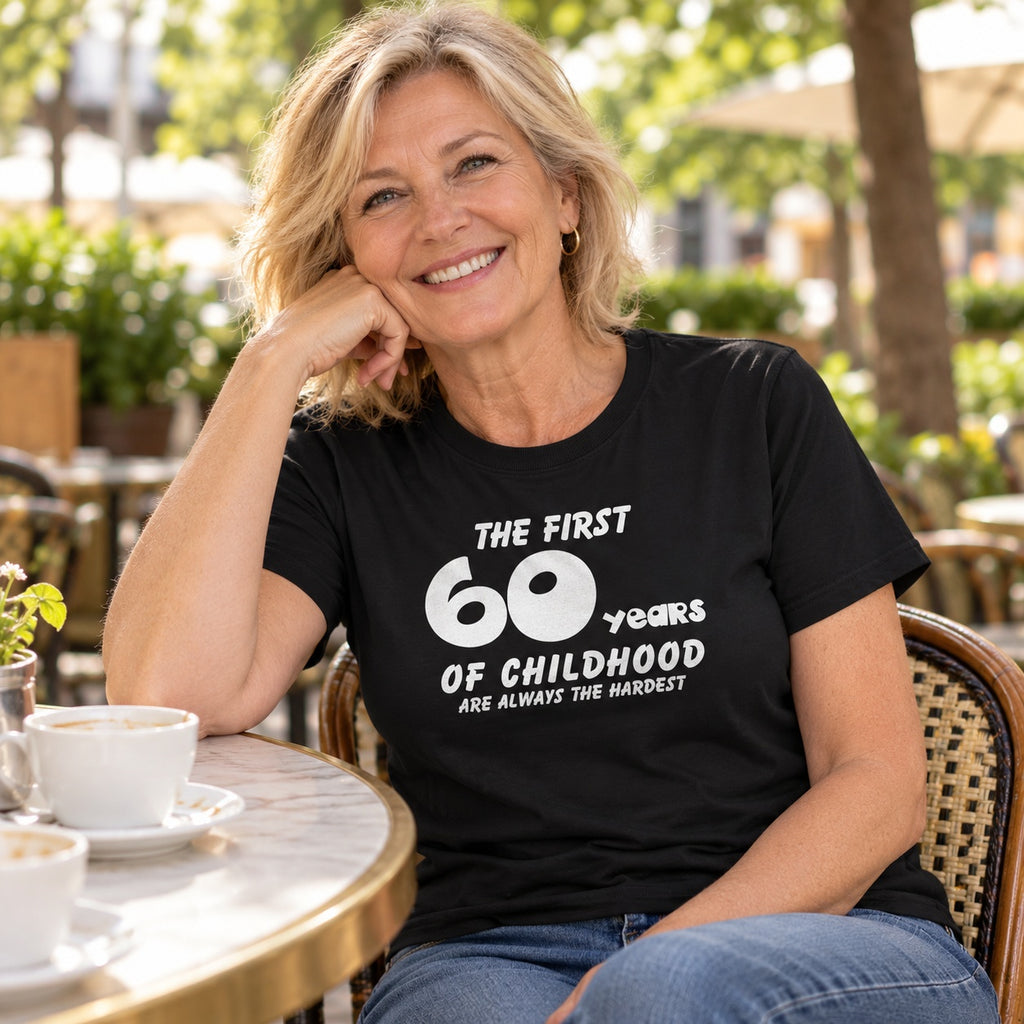 The First 60 Years of Childhood T-shirt in black - smiling woman at a café table with a cup of coffee, 60th birthday gift