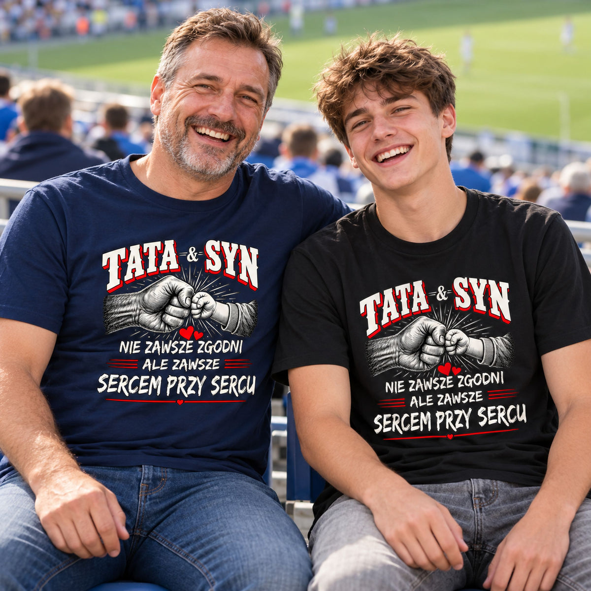Tata w granatowej koszulce i syn w czarnej koszulce TATA & SYN śmieją się na trybunach stadionu.