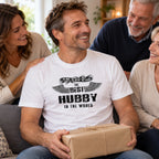The Best Hubby In The World wings T-shirt in white - man laughing with his family as he opens a present, funny gift for him from his wife