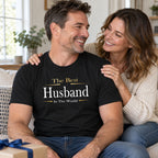 Husband in a black The Best Husband In The World Exclusive t-shirt on the sofa with his wife, anniversary gift with a wrapped box
