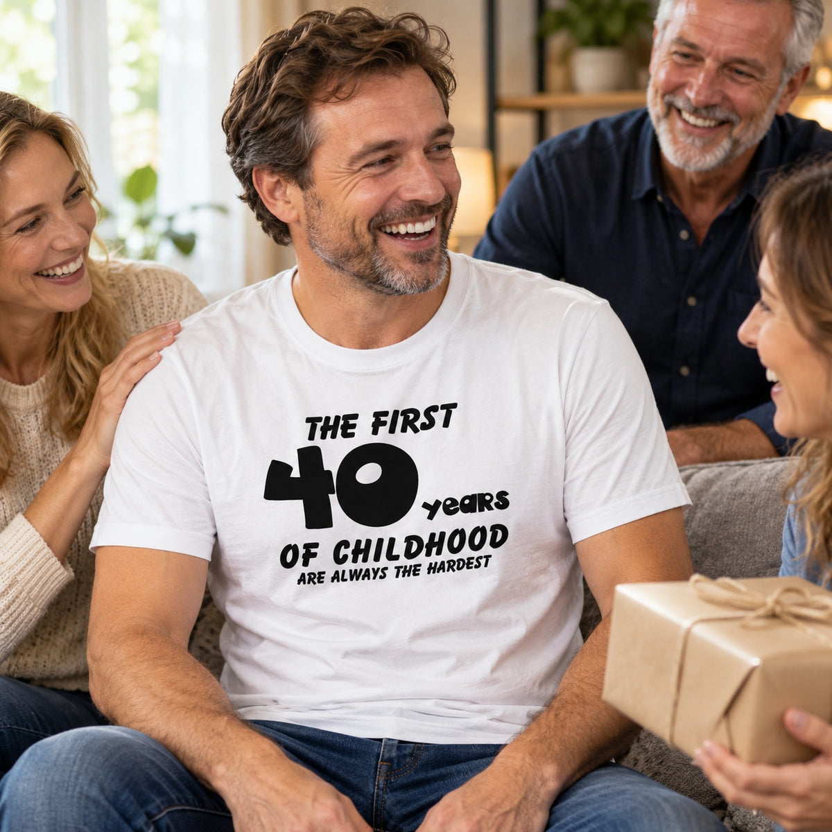 The First 40 Years of Childhood T-shirt in white - laughing man opening a birthday present with family, 40th birthday gift