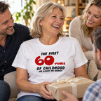 The First 60 Years of Childhood T-shirt in white with a red 60 - laughing woman holding a birthday present with friends, 60th birthday gift