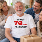 The First 70 Years of Childhood T-shirt in white with a red 70 - laughing grandad with a birthday present and his family, 70th birthday gift