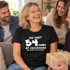 Personalised The First 54 Years of Childhood T-shirt in black - laughing woman holding a birthday present with her family, custom age gift