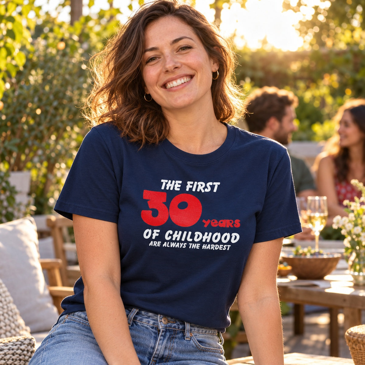 The First 30 Years of Childhood T-shirt in navy with a red 30 - woman at a sunny garden party with friends, funny 30th birthday shirt