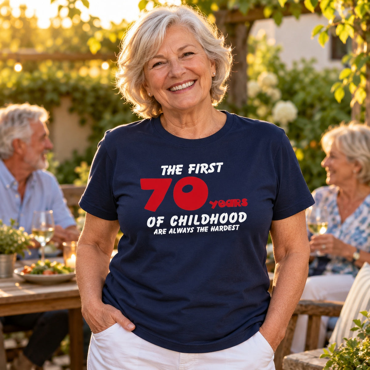 The First 70 Years of Childhood T-shirt in navy with a red 70 - smiling woman at a garden lunch with friends, funny 70th birthday shirt